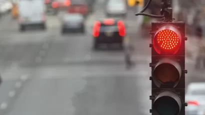 Close-up on red traffic light with blurred street in background.
