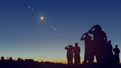 Sillhouettes of group of people watching solar eclipse.