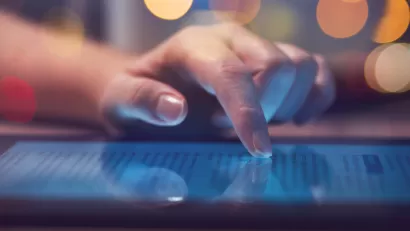 Close-up of hand scrolling through text website on tablet lying on table.