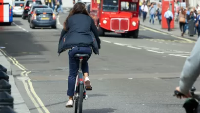 Woman rides a bike on street in London, UK.