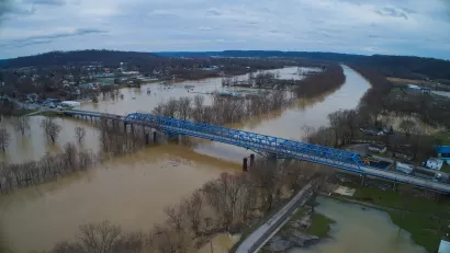 Aerial view of a blue bridge over a wide, flooded river in Kentucky.