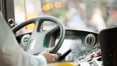 Close-up of bus driver holding bus steering wheel