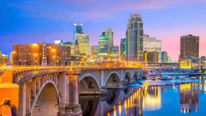 Late evening view of downtown Minneapolis skyline with stone bridge in foreground