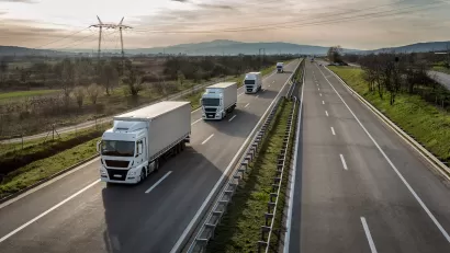 Aerial view of a line of freight trucks driving on a country highway.