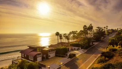 View of oceanfront homes in Malibu, California against golden afternoon sky