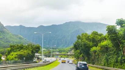 Traffic on Hawaii highway with green mountains in background