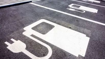 Close-up of white electric car charging symbol on black pavement in parking spaces.