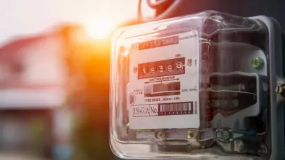 Close-up of electricity meter on house with sunset light in background.