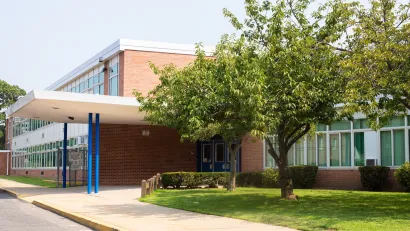 Brick school building with mid-sized tree on front lawn.