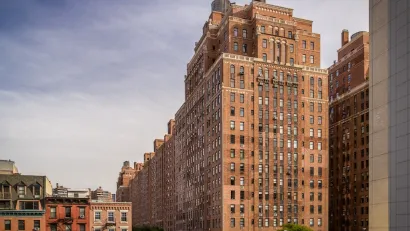 Tall red brick public housing building in New York City surrounded by shorter apartment buildings.