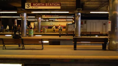 Few passengers waiting in subway station with multiple platforms and "North Station" signs in Boston, Massachusetts
