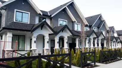 ROwn of grey and white townhomes with gabled roofs and front porches.
