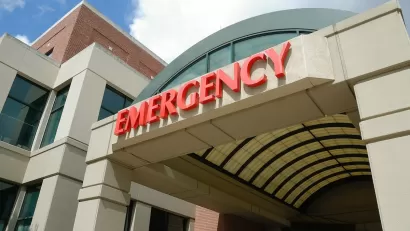 Close-up of red EMERGENCY sign above hospital emergency room entrance.
