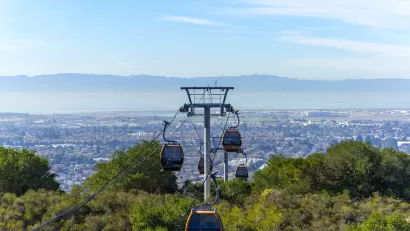 View of aerial tram cars at Oakland Zoo with Oakland, California neighborhoods in background.