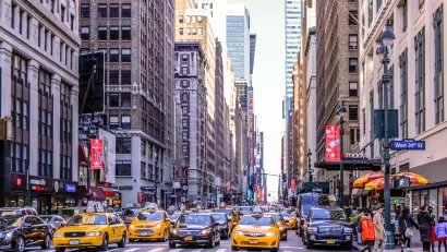 Intersection on Manhattan street with yellow cabs and black cars waiting for stoplight.