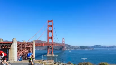 Two cyclists on a paved bike path overlooking the Golden Gate Bridge, San Francisco, California.