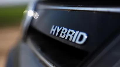 Close-up of HYBRID logo on back of black car.