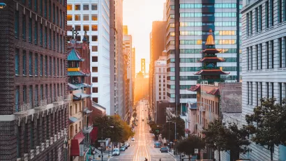 View down California Street in San Francisco, California with Chinatown pagoda buildings and golden hour sky in background.