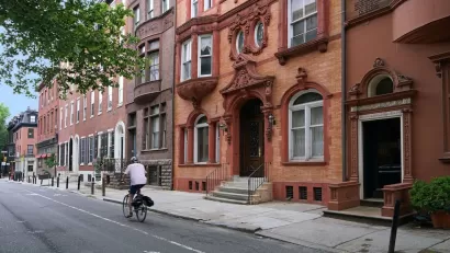 Person on bike rides in marked bike lane with brownstone homes in background in Phialdelphia, Pennsylvania.