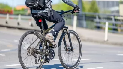 Close-up of person on bike wearing backpack riding on city street.