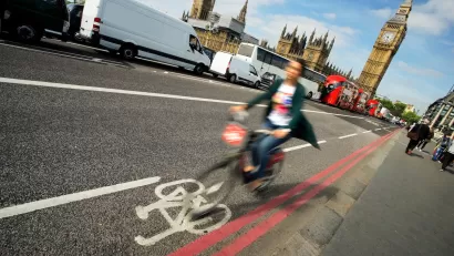 Blurry person in bike riding quickly in bike lane with Big Ben in background in London, UK.
