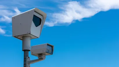 Close-up of speed camera against blue sky.