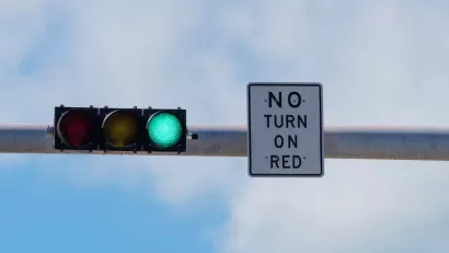Overhead traffic light with green light on and white "No turn on red" sign.