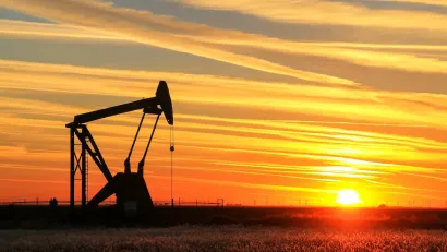 Oil pumpjack in a field at sunset.