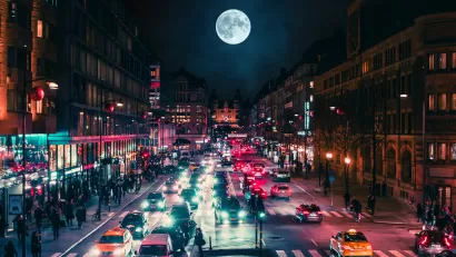 View of busy street at night with full moon in background in Stockholm, Sweden