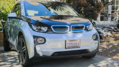 Silver electric BMW car parked in driveway of home in Oakland, California.