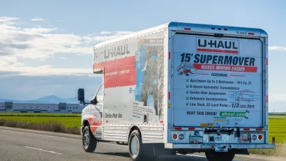 U-Haul truck on road with blurred grassy roadside in background.