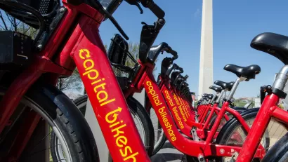 Close-up of red Capital Bikeshare bikes with Washington Monument in background.