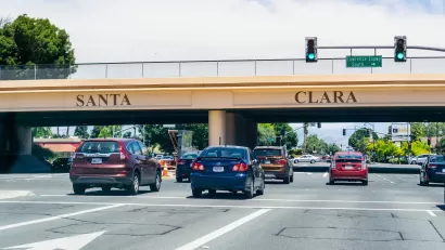 Cars passing under 101 freeway overpass with SANTA CLARA in large letters on the overpass