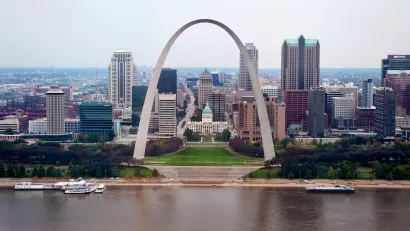 View of the Gateway Arch with Mississippi River in foreground and St. Louis skyline in background.