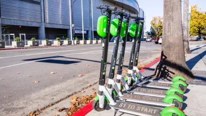 Several Lime e-scooters lined up next to curb on a sidewalk in San Jose, California.