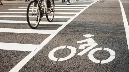Low angle of pedestrians and a bicycle crossing the street at an urban crosswalk.
