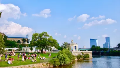 Riverfront park in Philadelphia with white gazebo and skyscrapers in background.