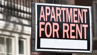 Close-up of "Apartment for rent" sign in red text on black background in front of blurred building