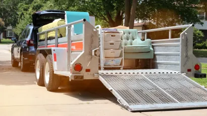 SUV with small open trailer hooked up filled with furniture for moving.