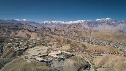 Aerial view of Rancho Mirage, California with homes in foreground and snowy San Gabriel Mountains in background.