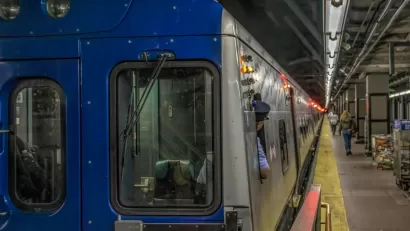 New York City subway train at station with operator looking back toward platform.