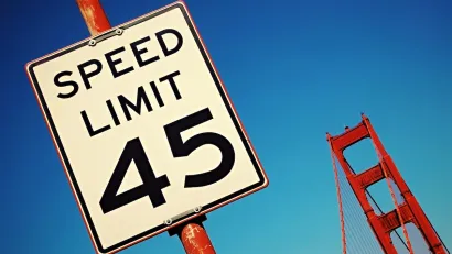 Close-up on 45 mph speed limit sign with part of Golden Gate Bridge visible in background, San Francisco, California.