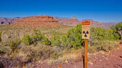 "Radiation Zone, Keep Out" sign on wood post with red Arizona desert mesa in background