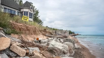 Houses on Lake Michigan shore with yellow "Keep Off Rocks" sign.