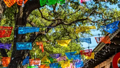 Colorful paper banners strung across street in historic tourist neighborhood in San Antonio, Texas.
