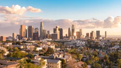 Downtown Los Angeles skyline viewed from the northwest on a sunny day with scattered clouds.