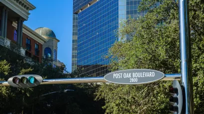 "Post Oak Boulevard" street sign in downtown Houston, Texas with glass high-rises in background.