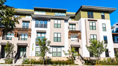 Four-story light-colored multifamily apartment building.
