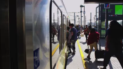 People boarding Los Angeles Metro train on outdoor platform.