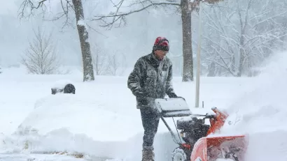 Man using snow plow during snowstorm.